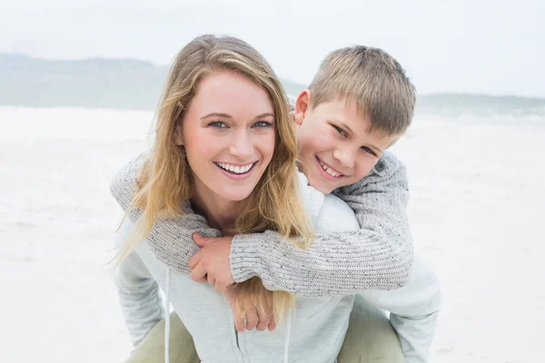 Vrouw meeliften haar zoon op strand — Stockfoto