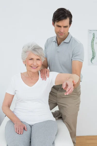 Mannelijke fysiotherapeut die zich uitstrekt van een senior vrouw arm — Stockfoto