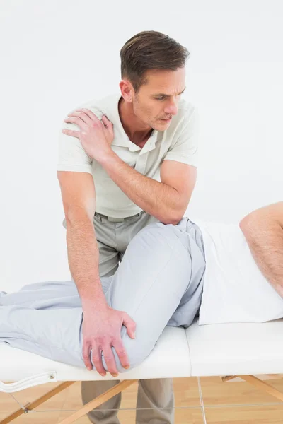 Fisioterapeuta masculino examinando a un hombre joven — Foto de Stock