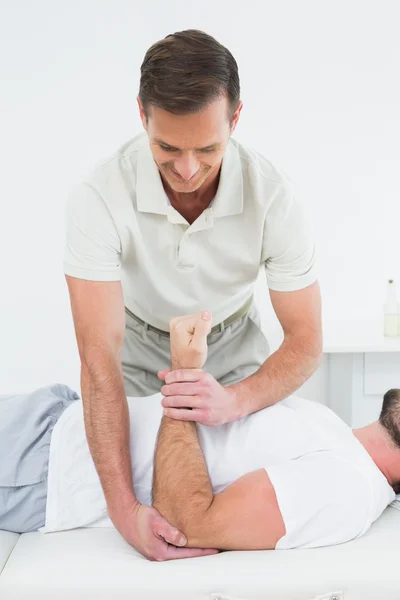 Fisioterapeuta masculino examinando a mão de um homem — Fotografia de Stock