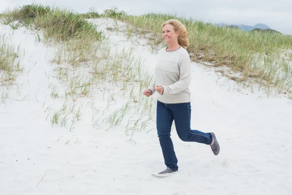 Happy senior kvinna kör på stranden — Stockfoto