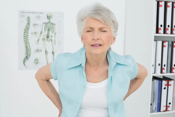 Senior woman with back pain in medical office — Stock Photo, Image