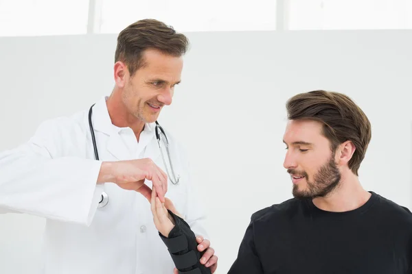 Fisioterapeuta masculino examinando o pulso de um jovem — Fotografia de Stock