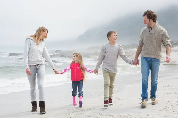 Lycklig familj av fyra promenader hand i hand på stranden — Stockfoto