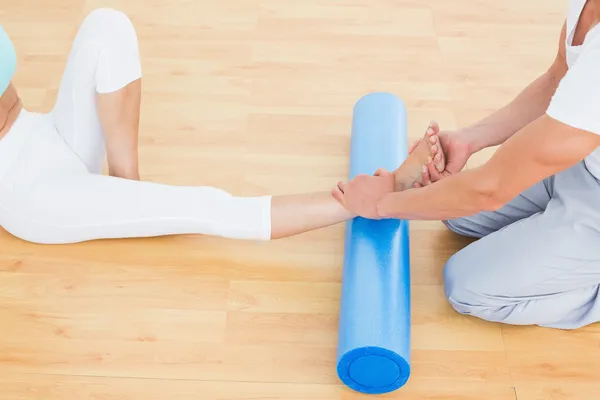 Physical therapist examining a young woman's leg — Stock Photo, Image