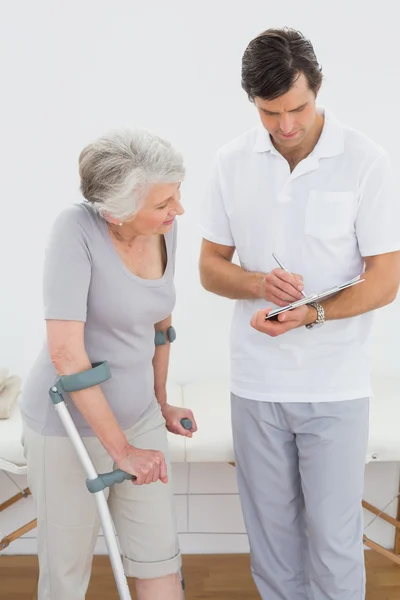 Therapist discussing reports with a disabled senior patient — Stock Photo, Image