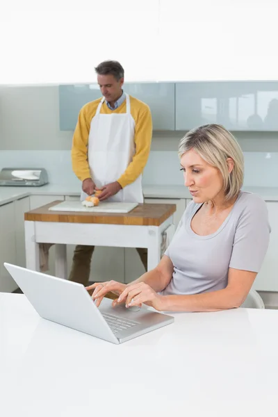 Vrouw met laptop en man hakken groenten — Stockfoto