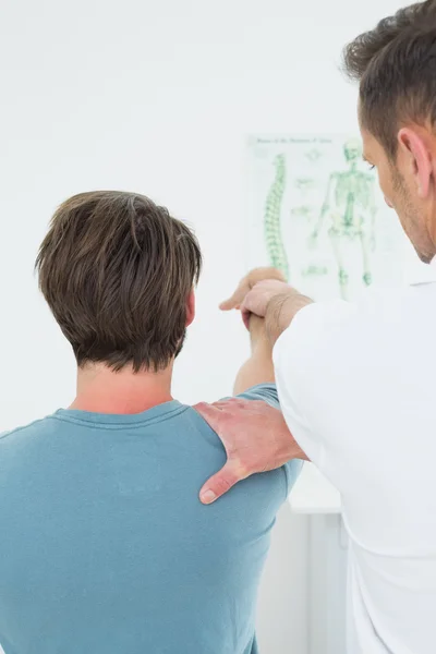 Vista trasera de un fisioterapeuta estirando el brazo de un hombre — Foto de Stock