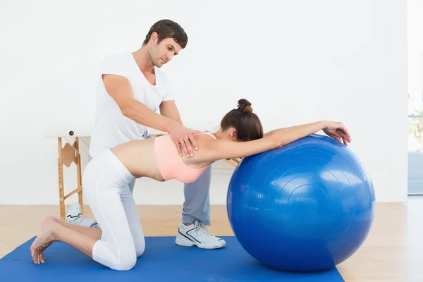 Fisioterapeuta asistiendo a mujer con bola de yoga — Foto de Stock