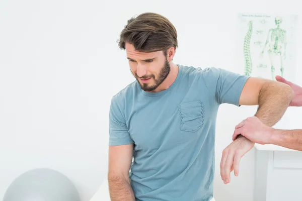 Fisioterapeuta masculino examinando el brazo de un joven — Foto de Stock