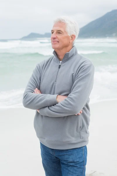 Созерцательный старший мужчина со сложенными руками на пляже — стоковое фото