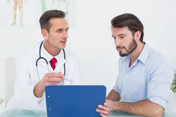 Médico discutindo relatórios com paciente em consultório médico — Fotografia de Stock