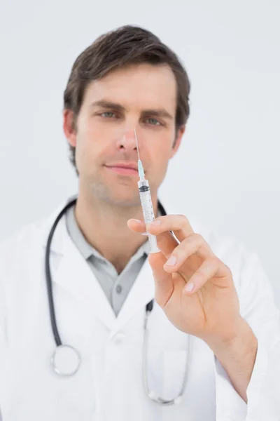 Portrait of a handsome male doctor holding an injection — Stock Photo, Image