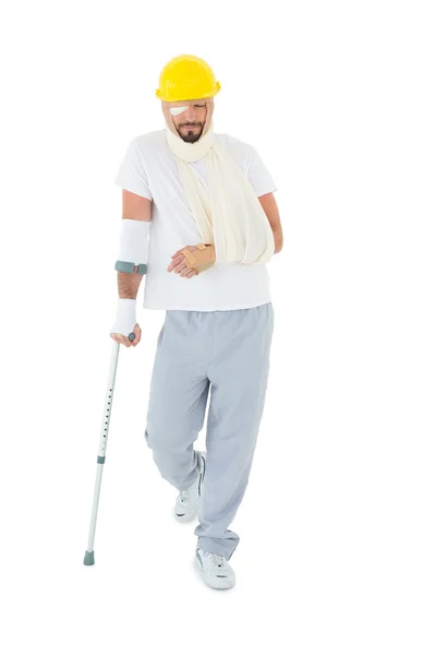 Man in hard hat with broken hand and crutch — Stock Photo, Image
