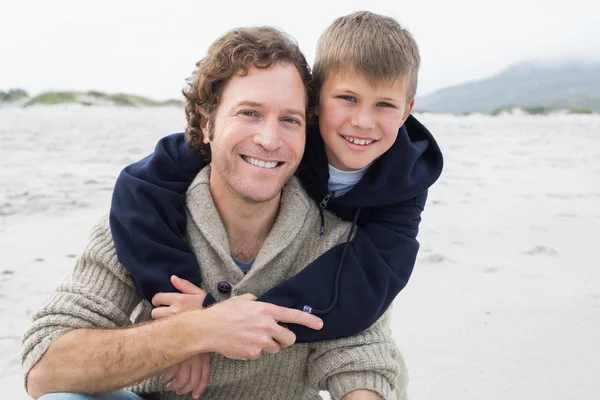 Homem piggybacking seu filho na praia — Fotografia de Stock