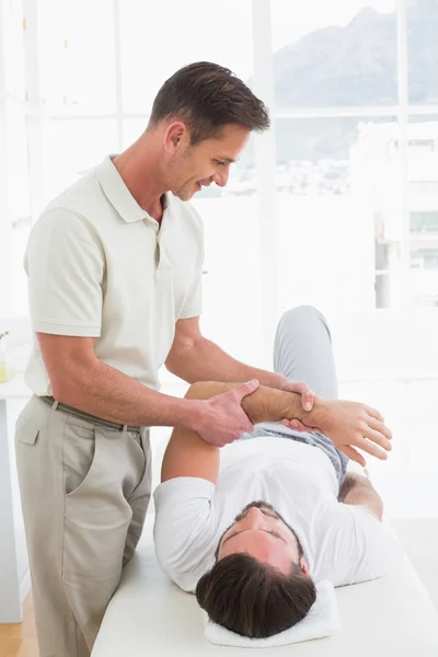 Fisioterapeuta masculino examinando la mano de un joven — Foto de Stock