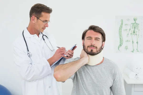 Médico masculino examinando el cuello torcido de un paciente — Foto de Stock