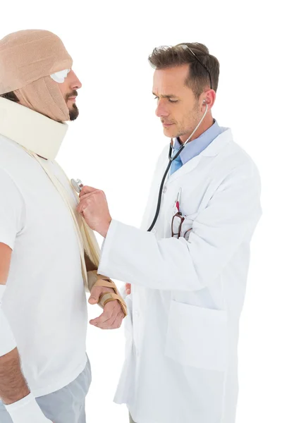 Médico auscultando paciente amarrado em curativo com estetoscópio — Fotografia de Stock