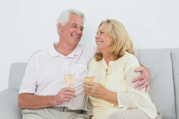 Äldre par med champagne flöjter hemma — Stockfoto
