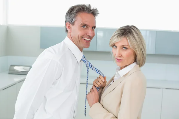 Vrouw met een gelukkig man door zijn das in keuken — Stockfoto