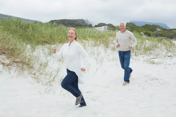 Cheerful senior couple running at beach — Stock Photo, Image