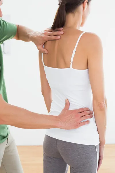 Физиотерапевт осматривает спину женщины в медицинском кабинете — стоковое фото