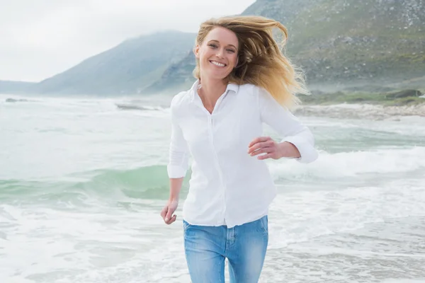 Портрет улыбающейся женщины, бегущей на пляже — стоковое фото