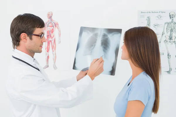 Врач-мужчина, объясняющий рентген легких пациентке — стоковое фото
