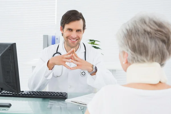 Lachende arts luisteren naar hogere patiënt op medische kantoor — Stockfoto
