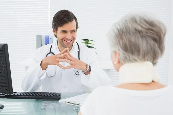 Médico sorridente ouvindo o paciente sênior no consultório médico — Fotografia de Stock