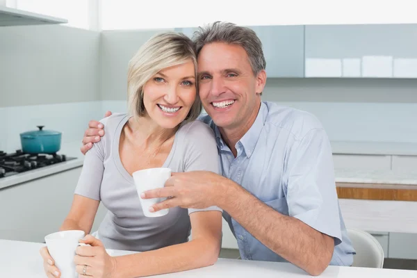 Счастливая любящая пара с чашками кофе на кухне — стоковое фото