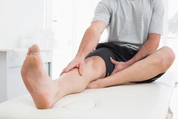Low section of a man with hands on a painful leg Stock Photo