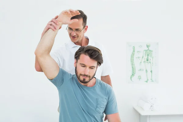 Male physiotherapist stretching a young man's arm — Stock Photo, Image