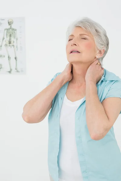 Femme âgée souffrant de douleurs au cou dans un cabinet médical Images De Stock Libres De Droits