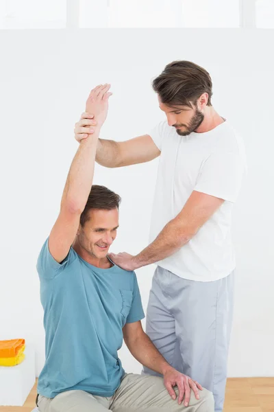 Physical therapist assisting man with stretching exercises — Stock Photo, Image