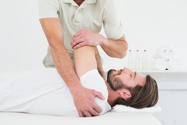 Male physiotherapist stretching a young man's hand Stock Photo