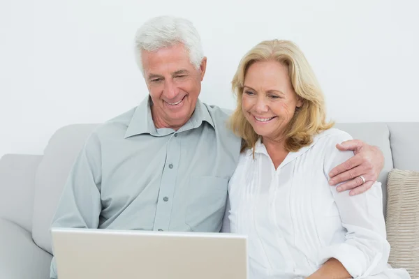 Relaxed senior couple using laptop at home Stock Picture