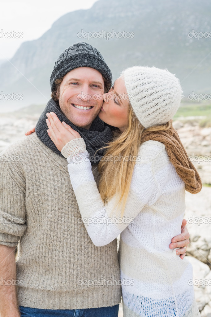 Woman kissing a man on rocky landscape
