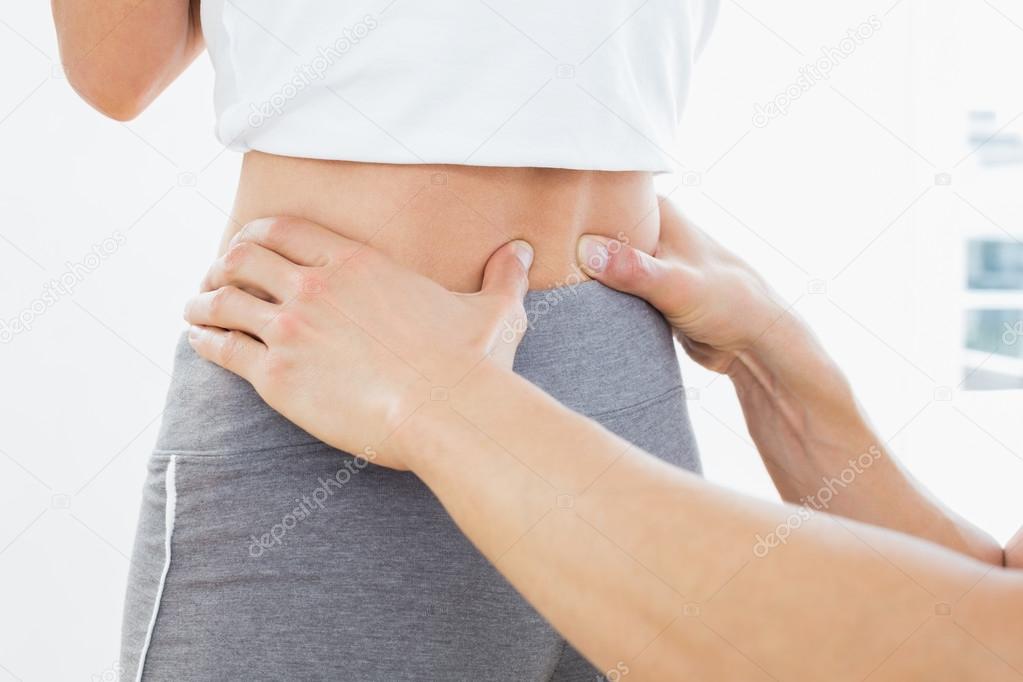 Mid section of a physiotherapist examining woman's back
