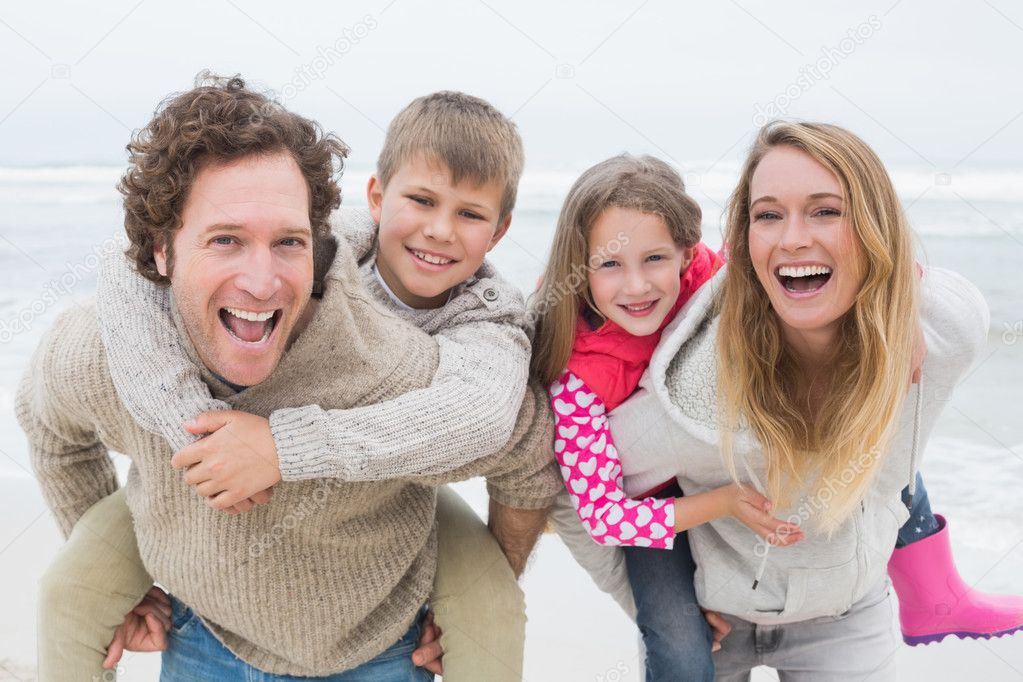 Couple piggybacking kids at the beach