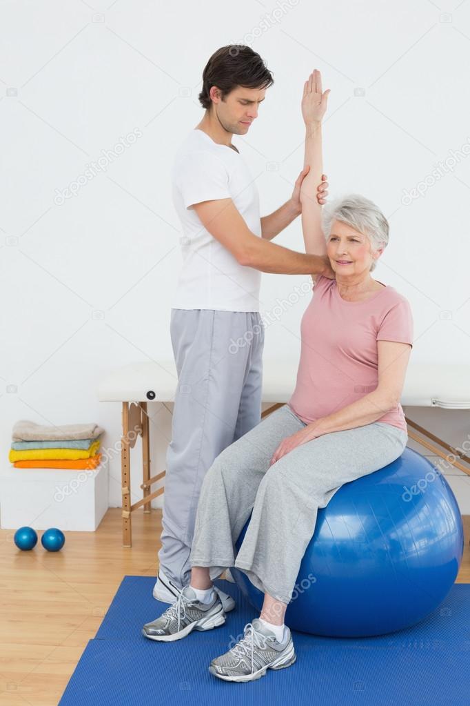 Senior woman on yoga ball with a physical therapist