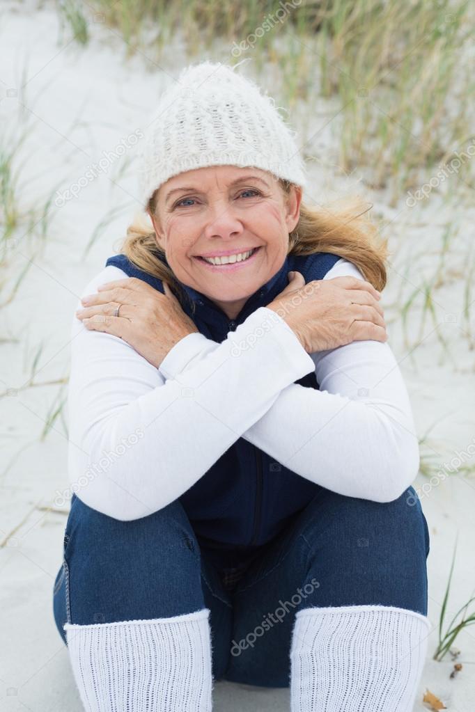 Happy senior woman feeling cold at beach