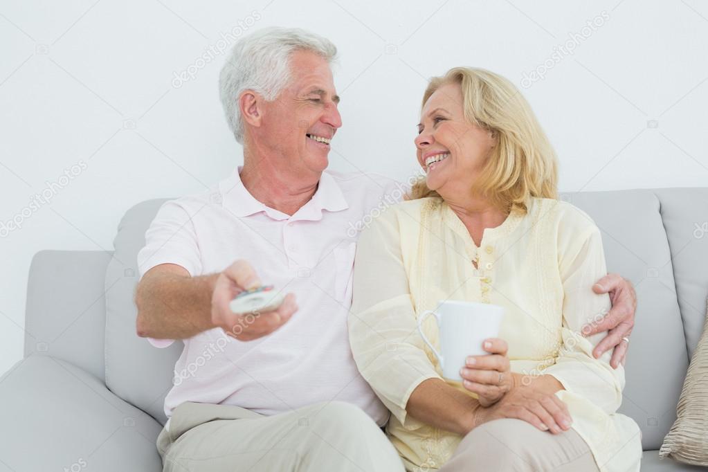 Cheerful senior couple watching television