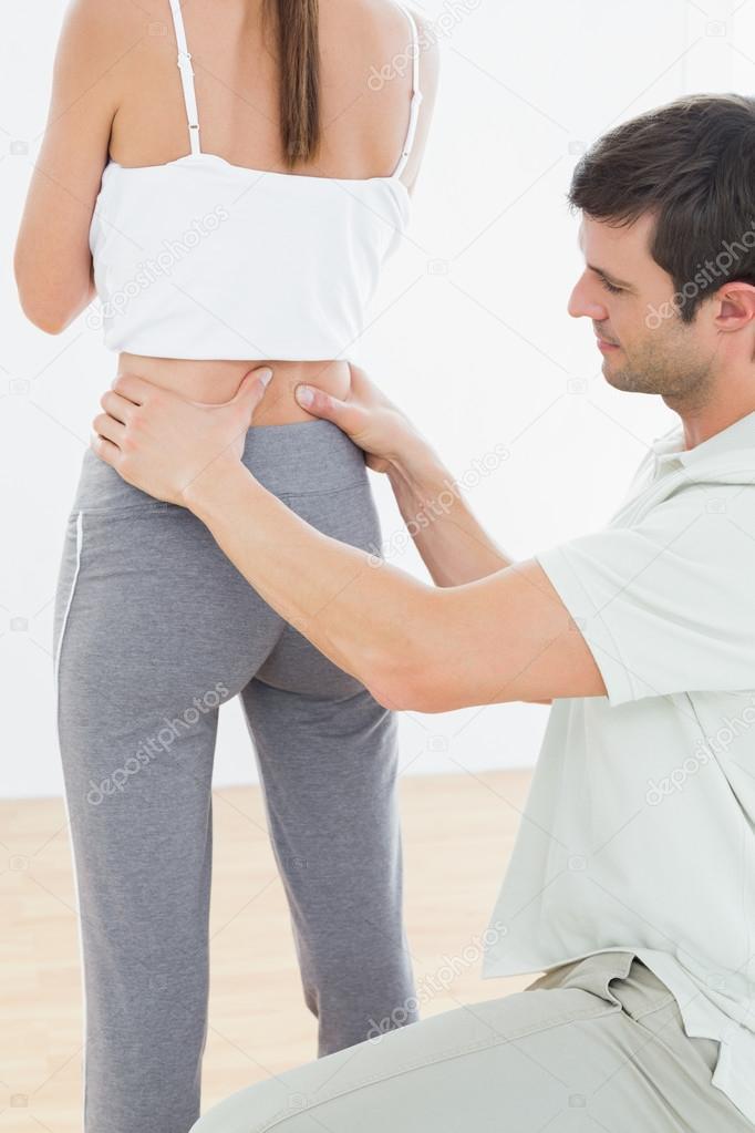 Rear view of a physiotherapist examining woman's back