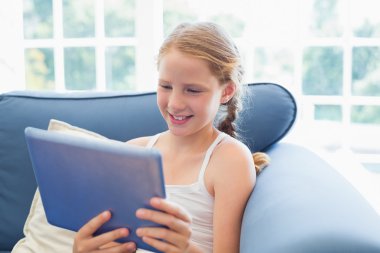 oturma odasında kanepede dijital tablet kullanarak rahat kız