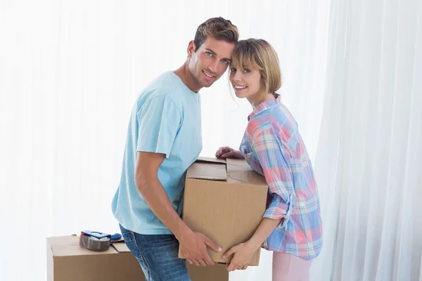 Casal feliz transportando caixa de papelão na casa nova — Fotografia de Stock