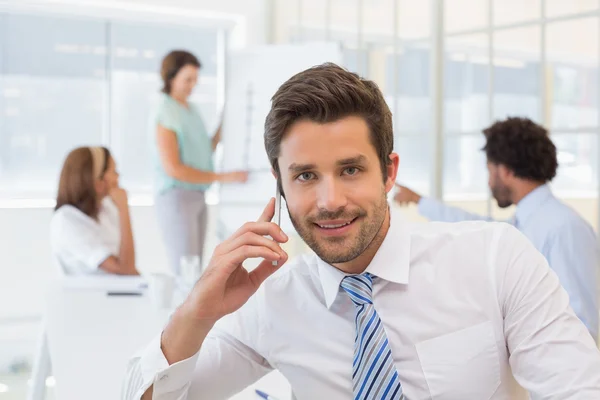 Smiling businessman on call with colleagues at office — Stock Photo, Image