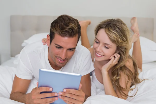 Entspanntes Paar lächelt mit digitalem Tablet im Bett — Stockfoto