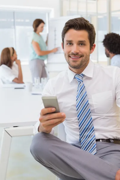 Mensajería de texto sonriente de hombre de negocios con colegas en la oficina — Foto de Stock