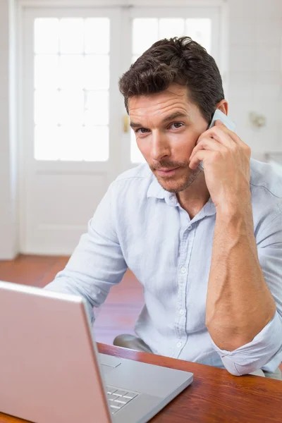 Uśmiechnięty mężczyzna za pomocą laptopa i telefon komórkowy — Zdjęcie stockowe